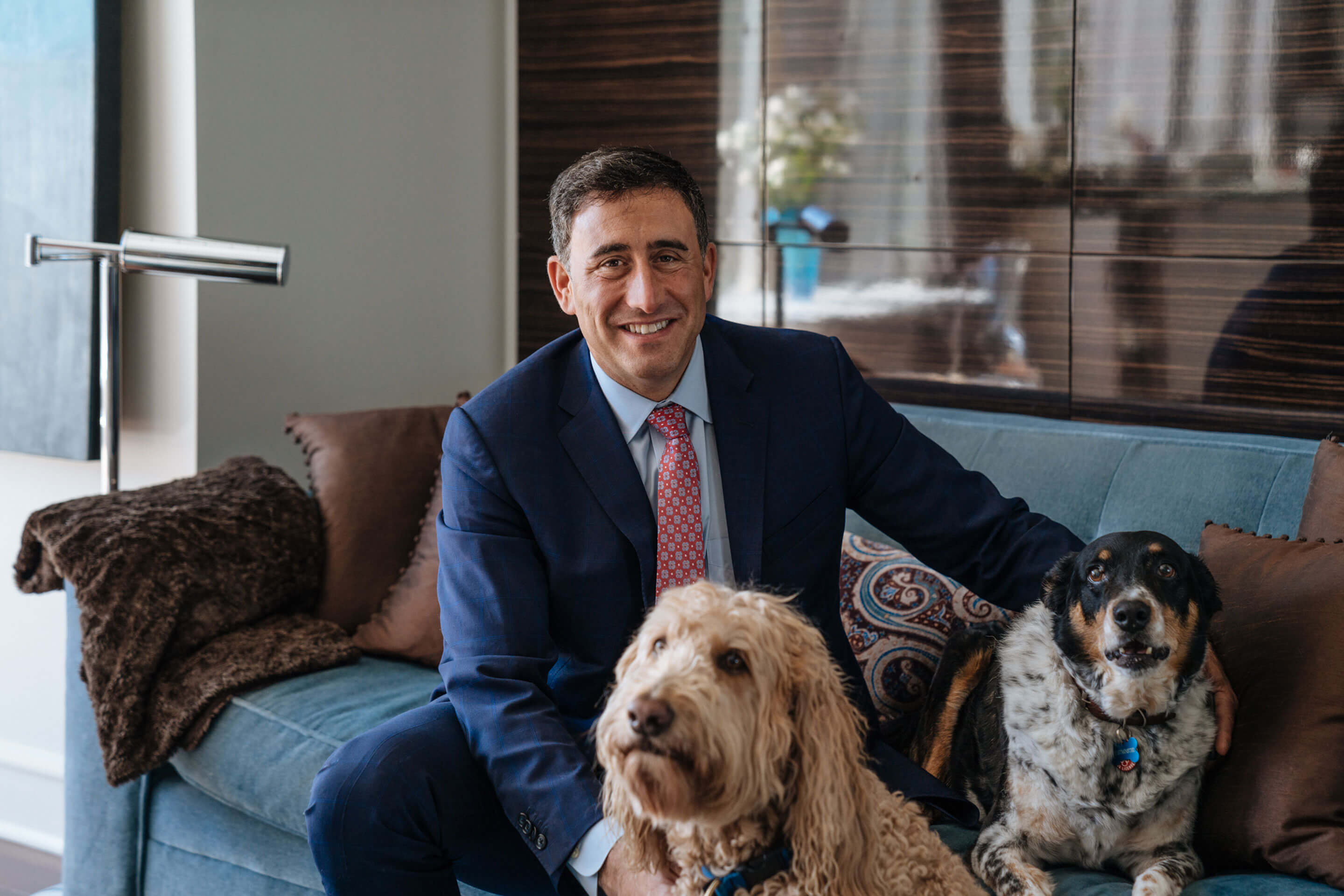 Agent Scott Stewart sitting on a couch with two dogs | Corcoran