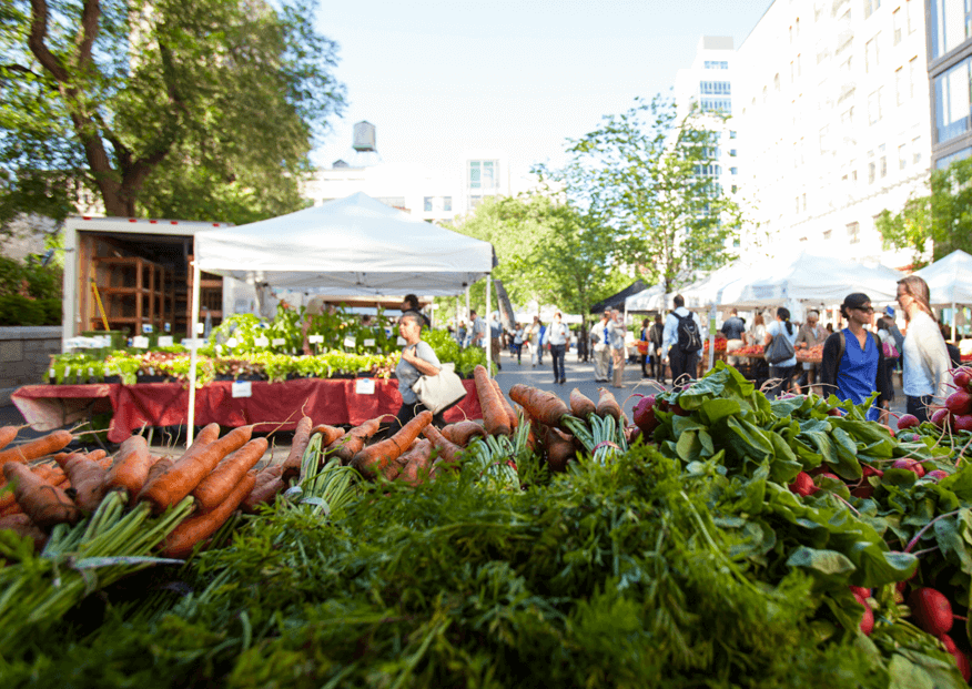 An NYC food market with a lot of food stands with fresh fruits and vegetables | Corcoran