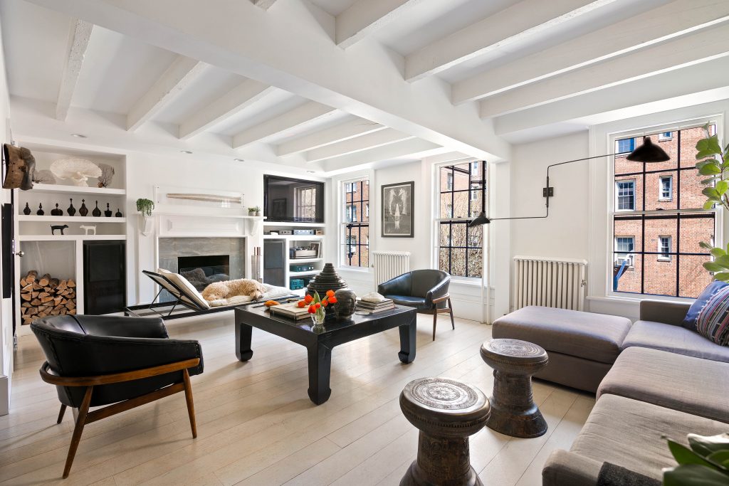 The living room at 148 Hicks Street, with a wood-burning fireplace, beamed ceilings, and a doodle resting on a lounger.