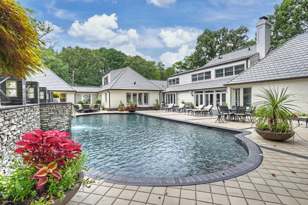 The rear of 1145 Crestbook Drive features a swimming pool with a waterfall.