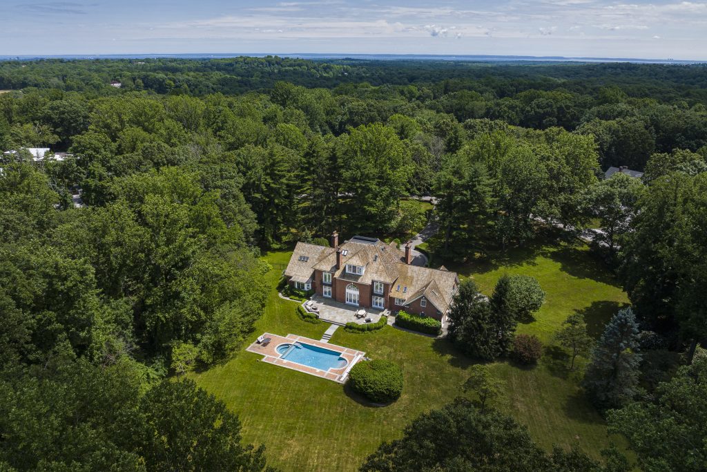 An overhead view of 36 Day Road, the backyard and swimming pool are visible behind the brick home among the sprawling Greenwich landscape.