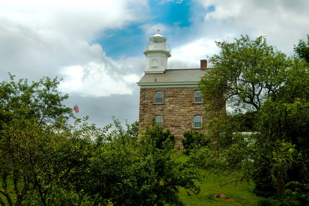 Peeking through the leafy shrubberies on Great Captain Island to look at the brick, granite, and cast iron Great Captain Island Lighthouse.