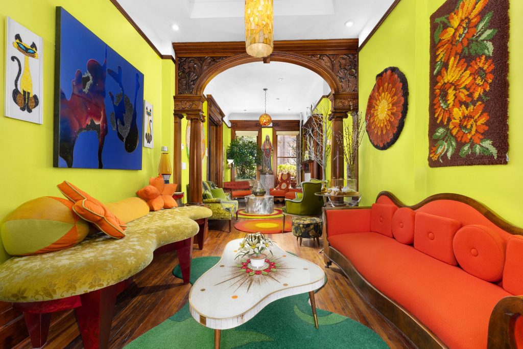 The vibrant parlor living room at 44 Hamilton Terrace features energetic yellow-green walls and an original hand-carved wooden archway by architect Henri Foucaux.