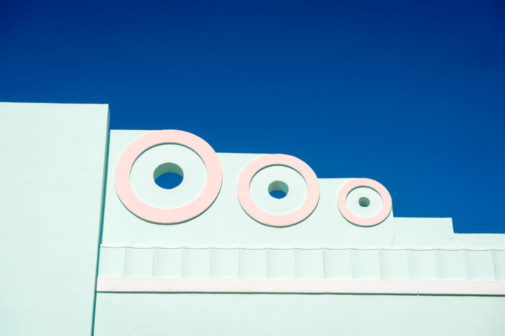 The top of this sea foam Art Deco building is stylized to feature circular holes.