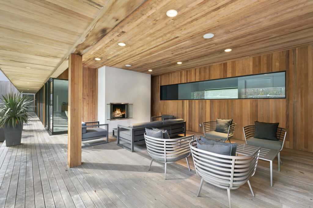 A covered outdoor living room with a wood-burning fireplace and ample seating area.