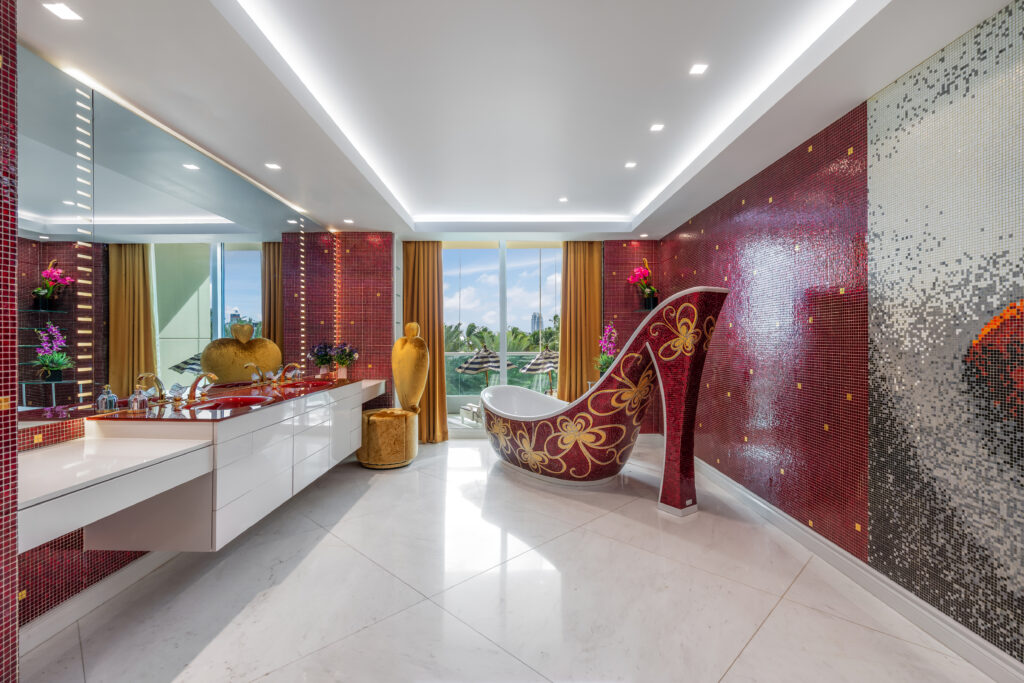 A bathtub shaped like a stiletto heel and bedecked in glittering red and gold tiles.