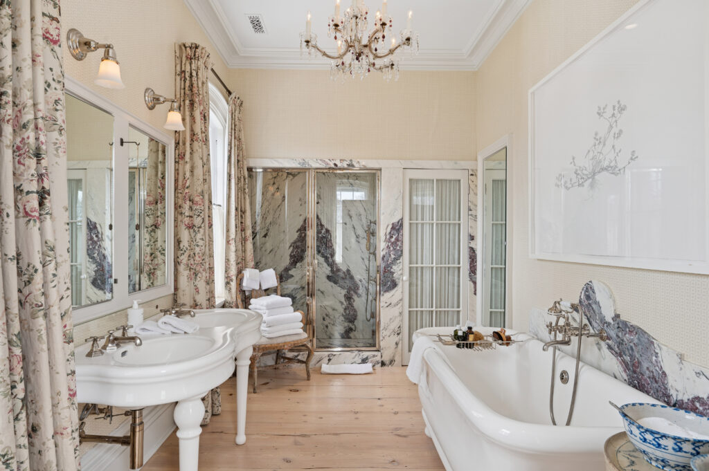The fixtures for this clawfoot bathtub emerge from a marble wall accent.