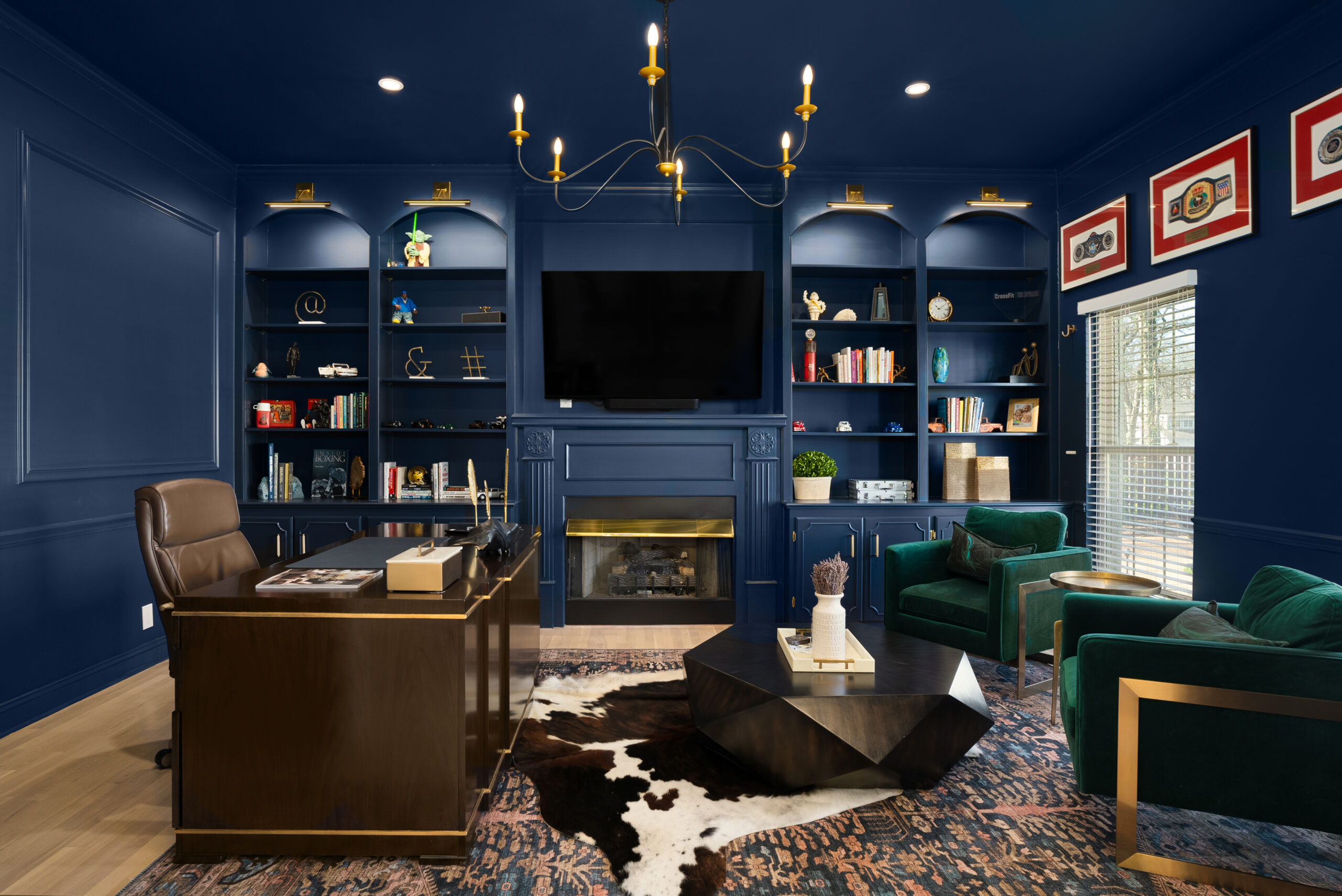 Dark blue home office or study with built in bookshelves and two rugs stacked on top of each other.