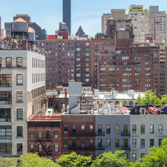 Cityscape featuring a mix of low-rise and high-rise buildings under a clear blue sky.