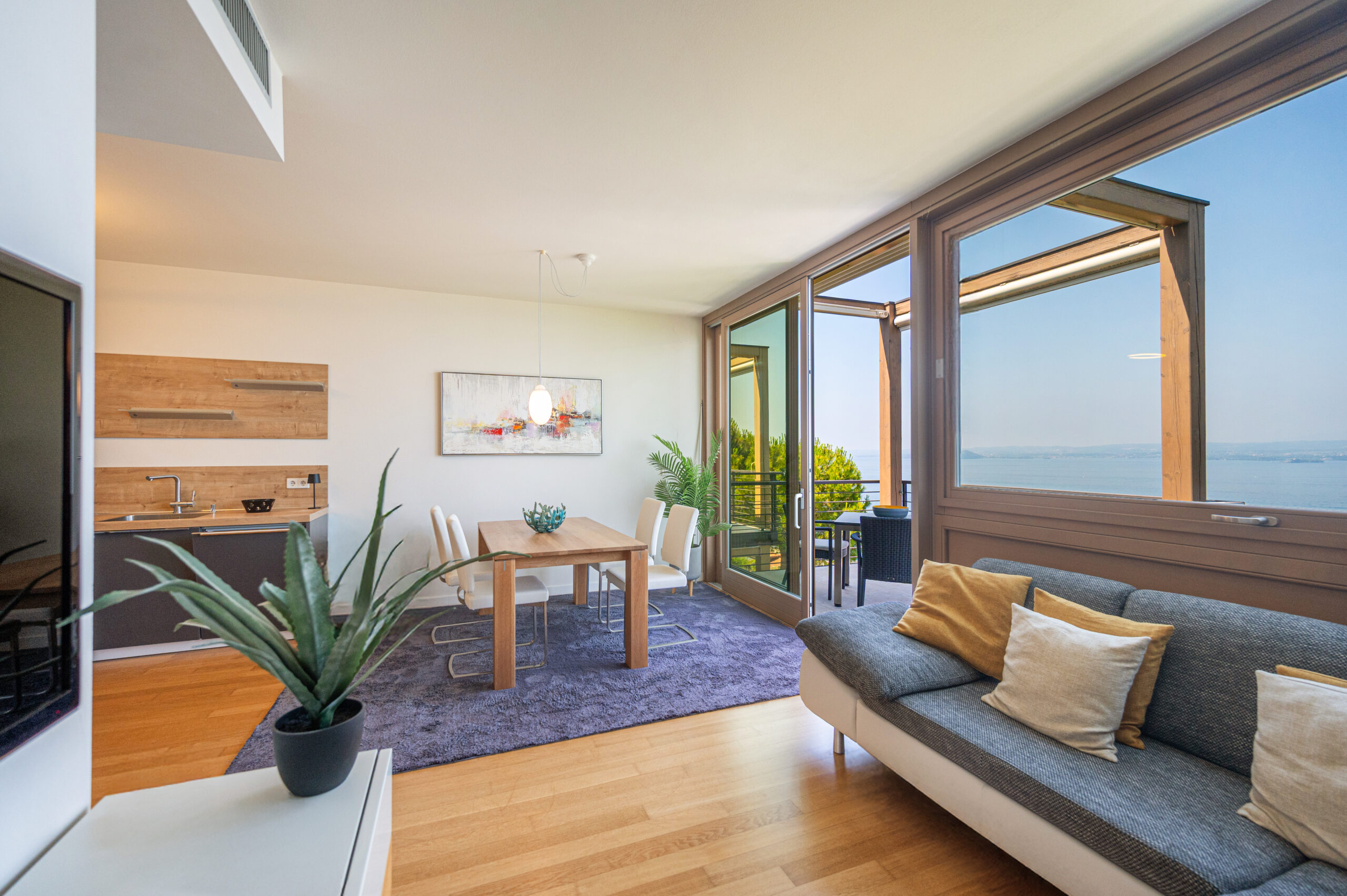 Living room with a sofa on one side with a view of Lake Garda out of the window.