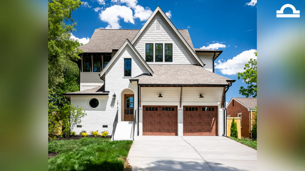 A modern two-story house with a white exterior, brown shingle roof, and two wooden garage doors.