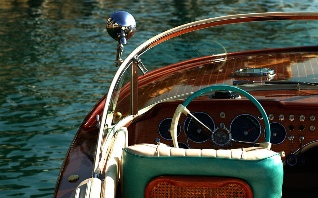Close-up of a vintage wooden motorboat’s cockpit, featuring a turquoise and cream steering wheel, leather seat with wicker back, and dashboard with gauges—perfect for relaxing on calm water with your favorite cookbooks onboard.