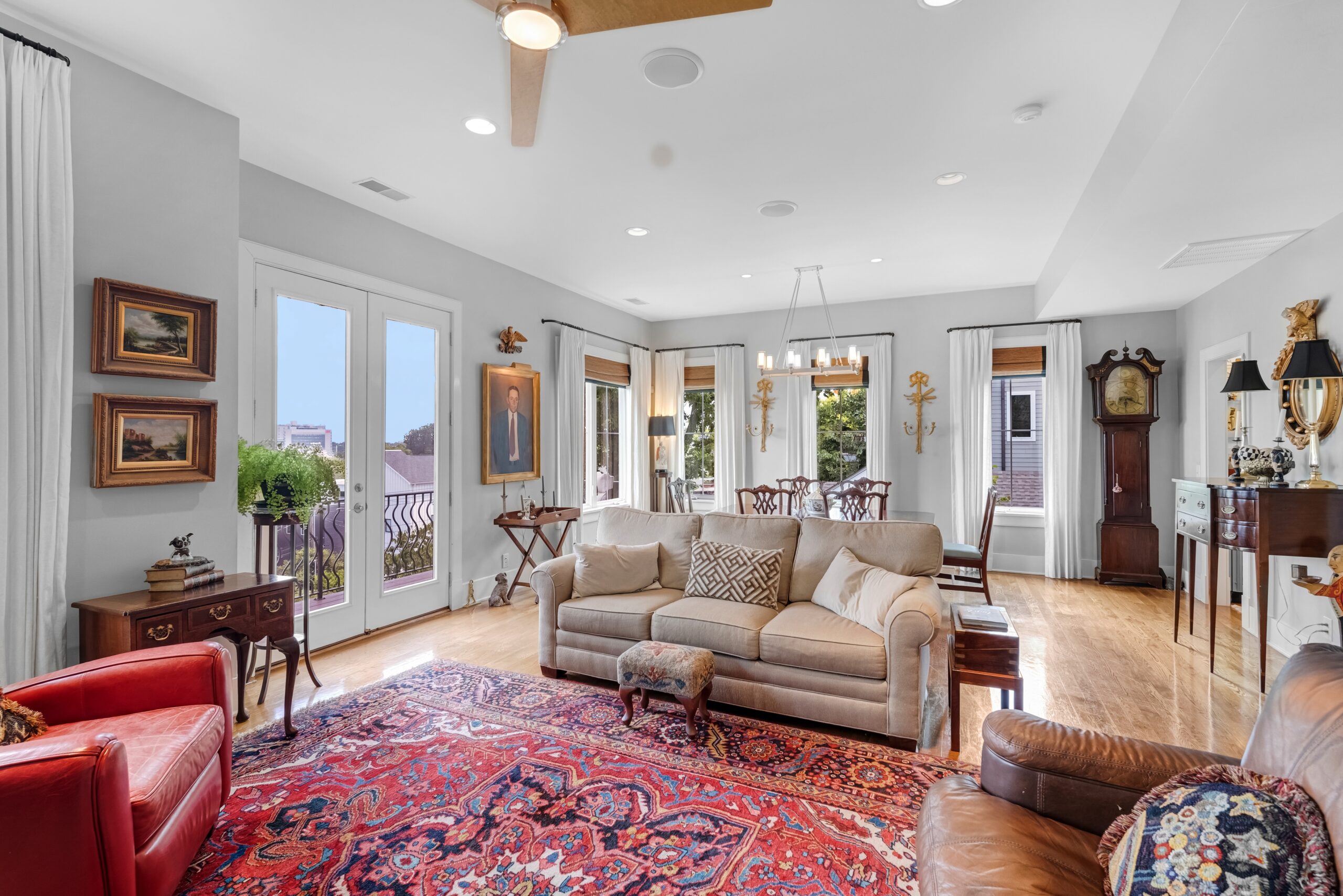 Elegant living and dining area with classic decor, vintage furniture, artwork on walls, a red patterned rug, large windows, and a chandelier—an inviting A-list space perfect for September 2025 gatherings.