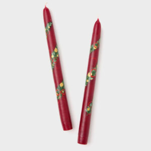 Two red taper candles with hand-painted floral designs in green, yellow, and white are placed side by side on a plain light background—perfect for brightening your dining table alongside cherished cookbooks.