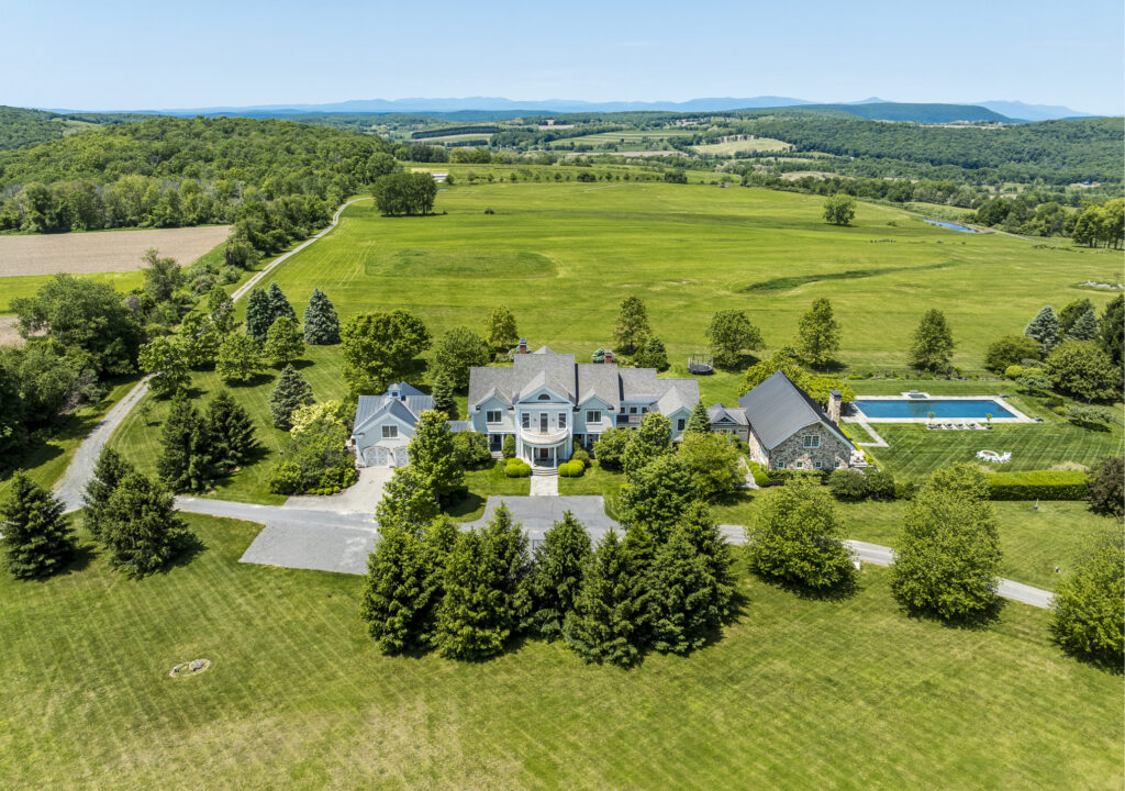 A large country estate with a circular driveway, surrounded by green lawns and trees, includes a main house, guest house, and backyard swimming pool—an idyllic retreat for reflection on astrological houses during Aquarius season.