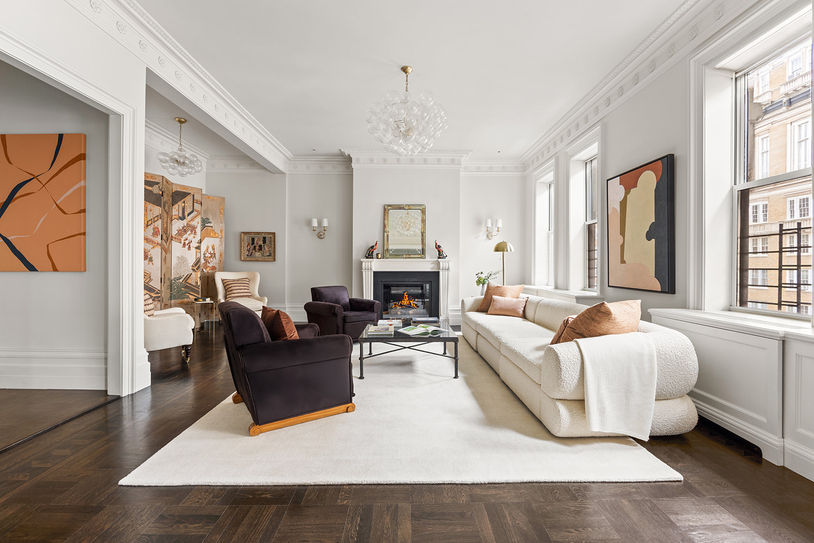 Elegant living room with modern decor, featuring a white sofa, dark armchairs, and large windows letting in natural light—a true a-list: March 2026 space. Dark wood floors and white walls create a bright, airy atmosphere.