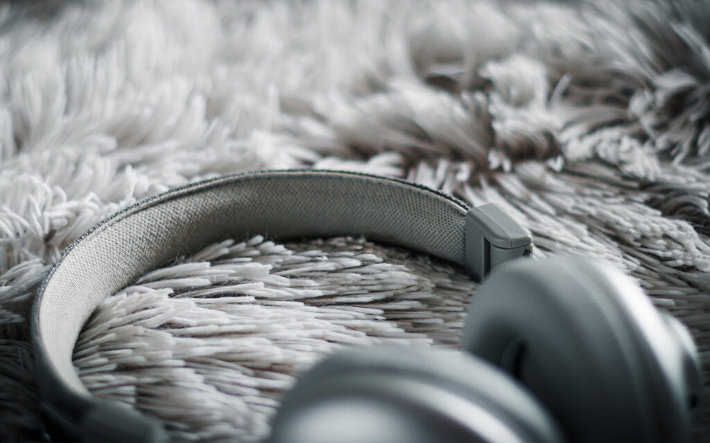 headphones_sm-2 A close-up of gray over-ear headphones resting on a soft, fluffy, light-colored rug—perfect for relaxing after a day of holiday decorating, with the headphone band and part of the ear cups in focus.