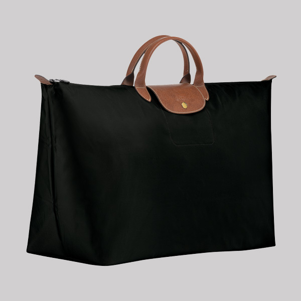A large black travel tote bag with two short brown leather handles and a gold button on the front, perfect for holiday decorating trips, photographed against a plain light gray background.