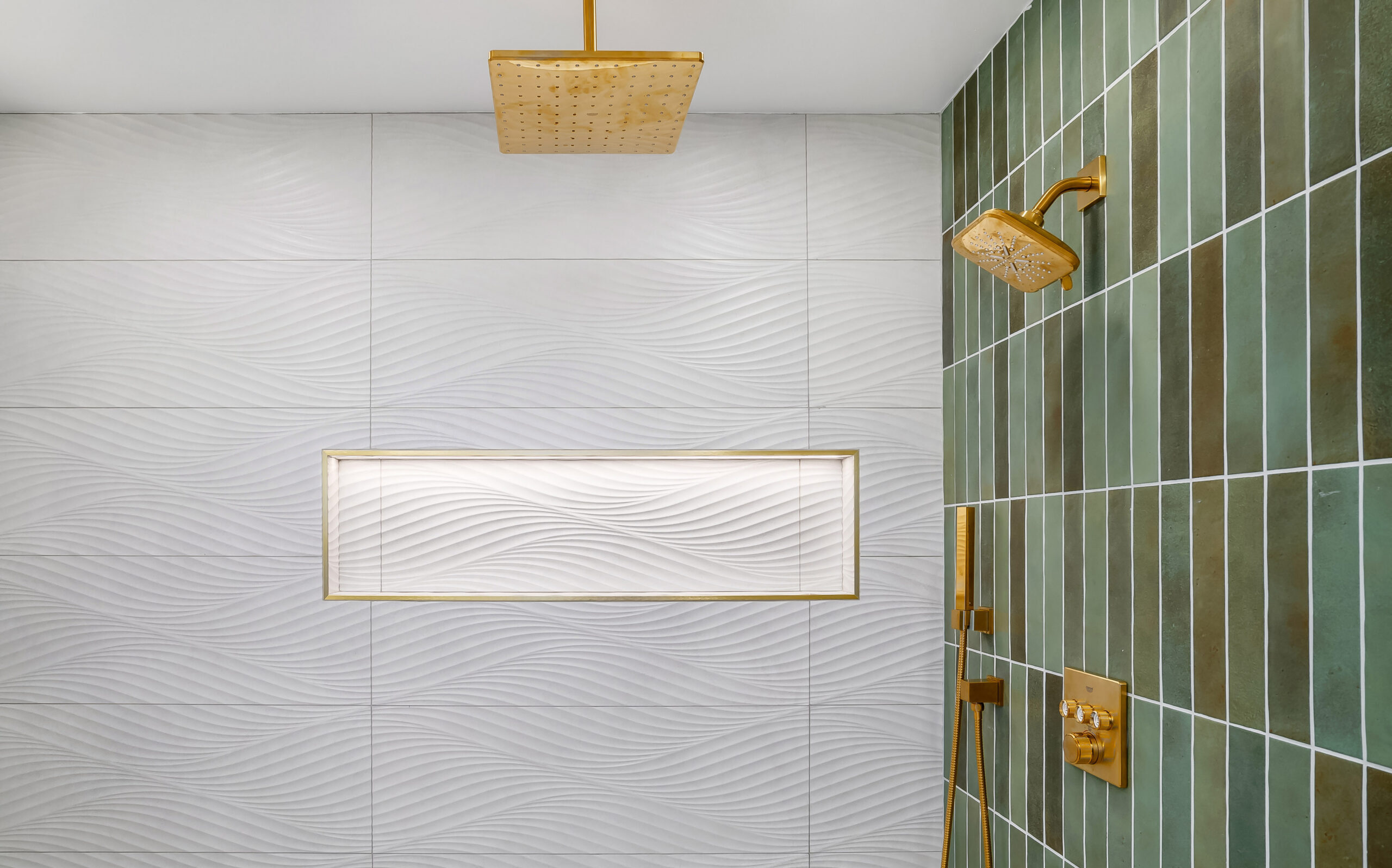 Modern shower with green vertical tiles on one wall, white textured tiles on the other, and gold fixtures—including a rainfall showerhead perfect for enjoying your own april showers. A rectangular niche is built into the white tile wall.