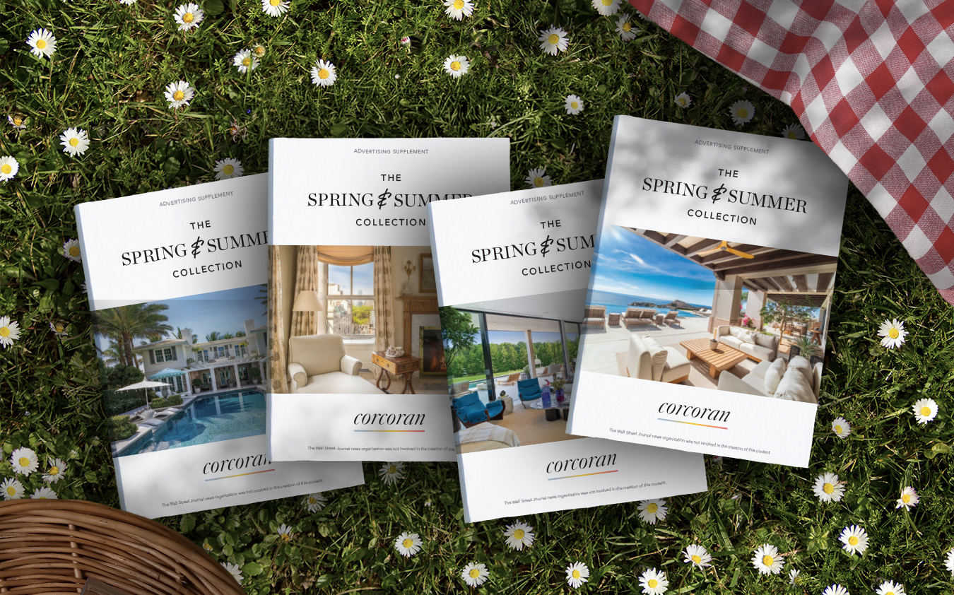 Four Spring & Summer Collection magazines with luxury home images on the covers are arranged on grass with daisies, next to a picnic blanket and basket.