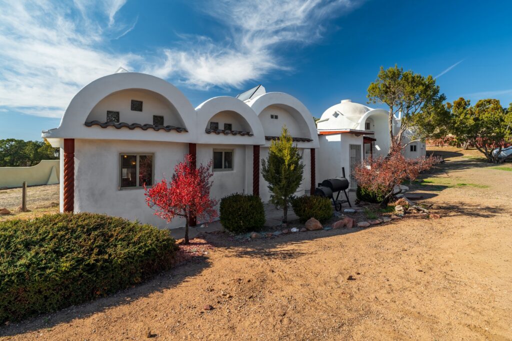 Southwestern-style guest house with white stucco walls, distinctive barrel-vault rooflines, desert landscaping, and adobe-inspired architecture, showcasing luxury Santa Fe living and unique regional design.