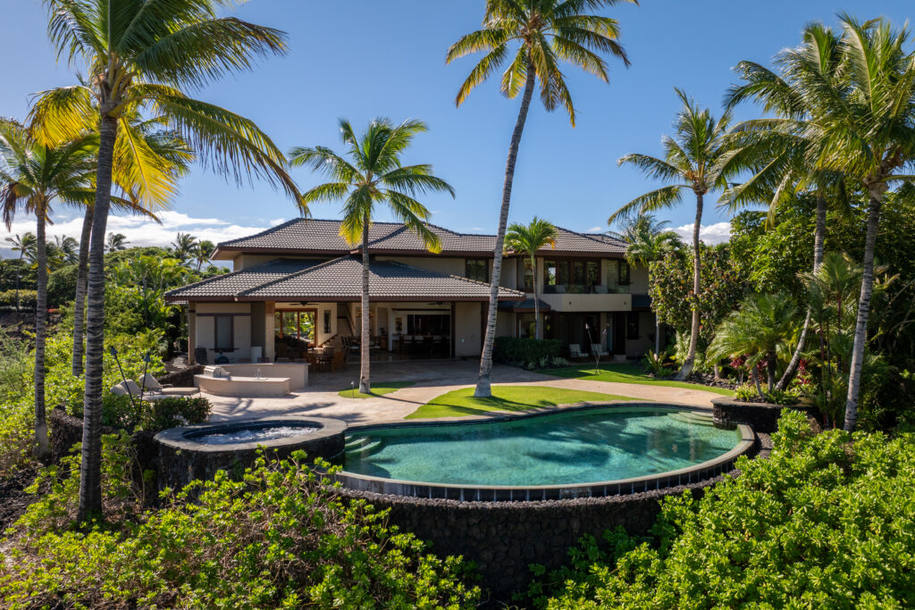 Scorpio A luxurious house with a swimming pool and spa surrounded by palm trees and lush greenery under a clear blue sky, perfectly reflecting the harmony of astrological houses during Virgo season.