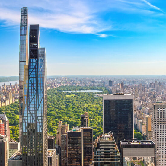 Aerial view of Central Park surrounded by skyscrapers in New York City on a clear day, with blue sky and scattered clouds above the city skyline—a stunning scene that reflects the vibrant energy driving Manhattan luxury sales.