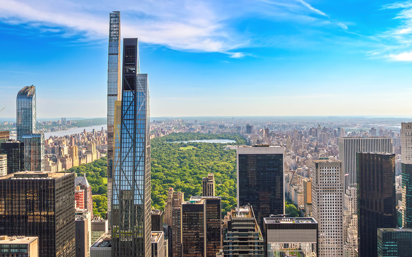 Aerial view of Central Park surrounded by skyscrapers in New York City on a clear day, with blue sky and scattered clouds above the city skyline—a stunning scene that reflects the vibrant energy driving Manhattan luxury sales.