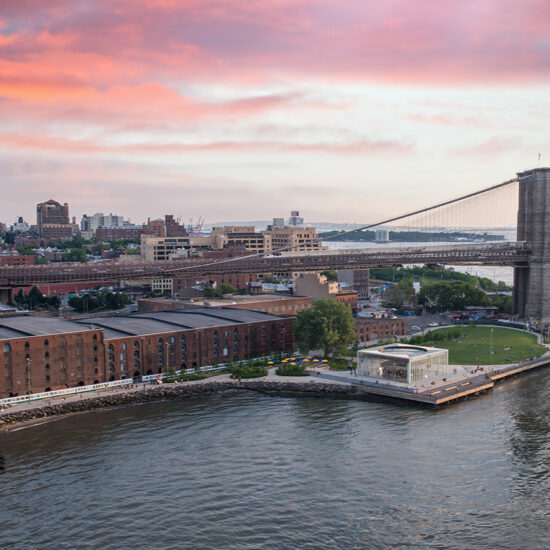 Aerial view of the Brooklyn Bridge, Brooklyn Bridge Park, and the East River at sunset.