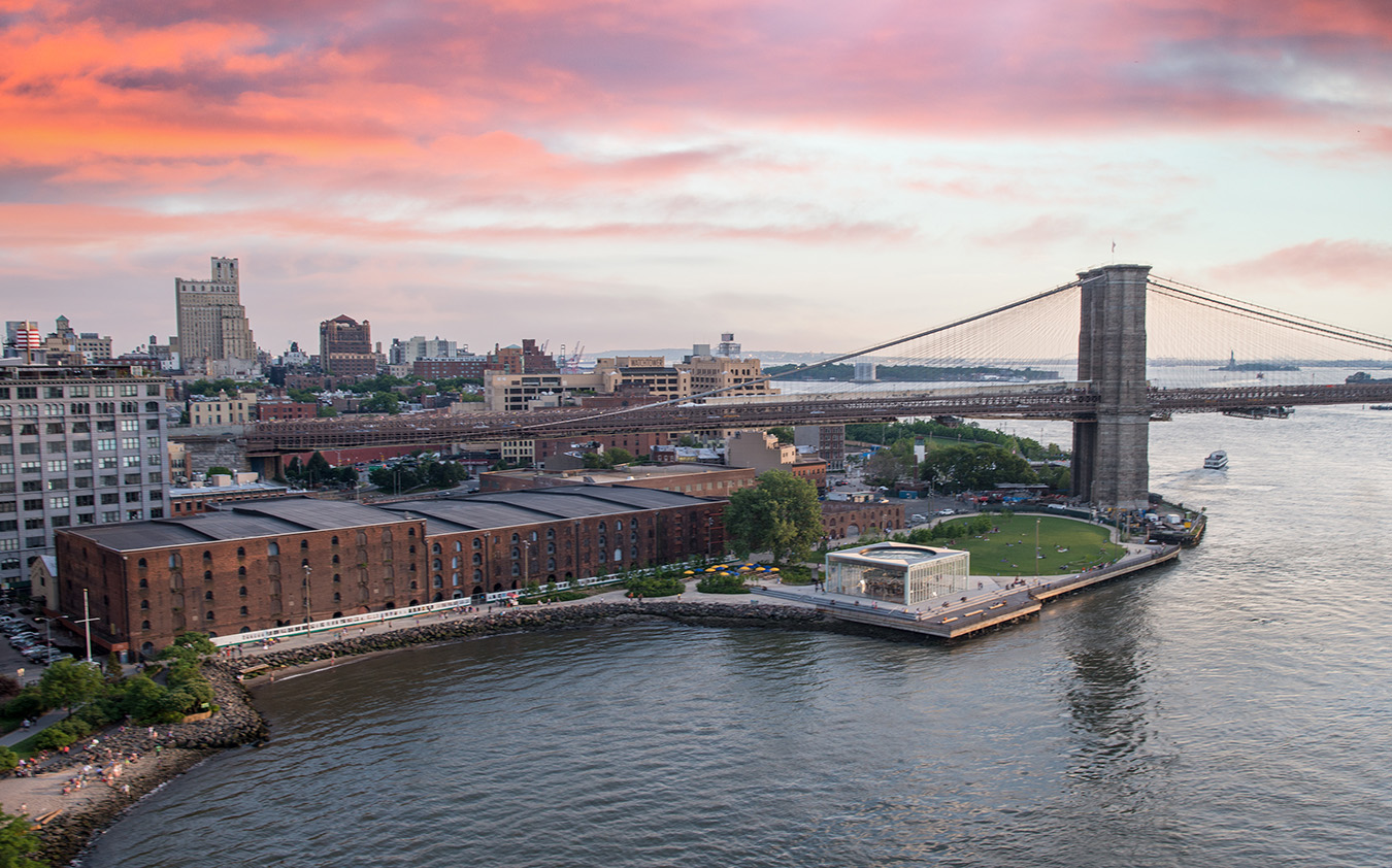 Aerial view of the Brooklyn Bridge, Brooklyn Bridge Park, and the East River at sunset.